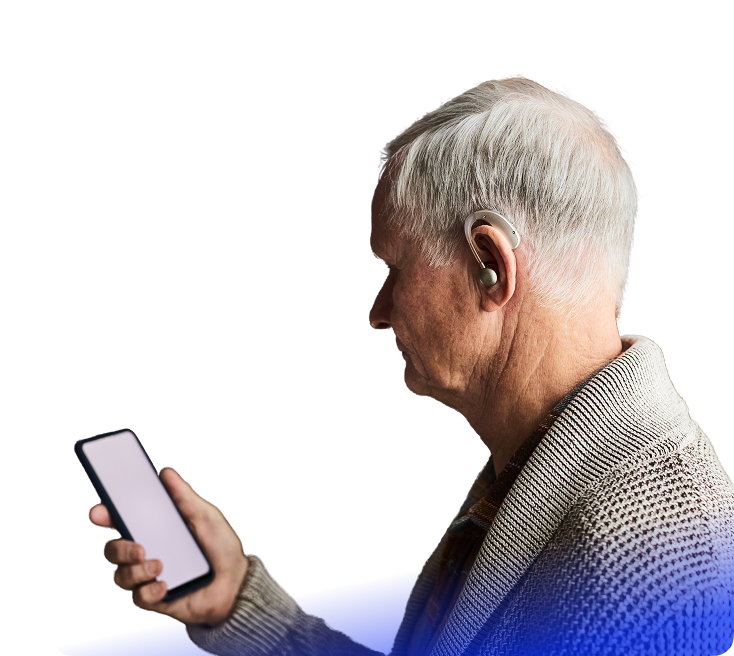 Beyaz saçlı yaşlı bir kişi elinde bir akıllı telefon tutuyor ve işitme cihazı takıyor.